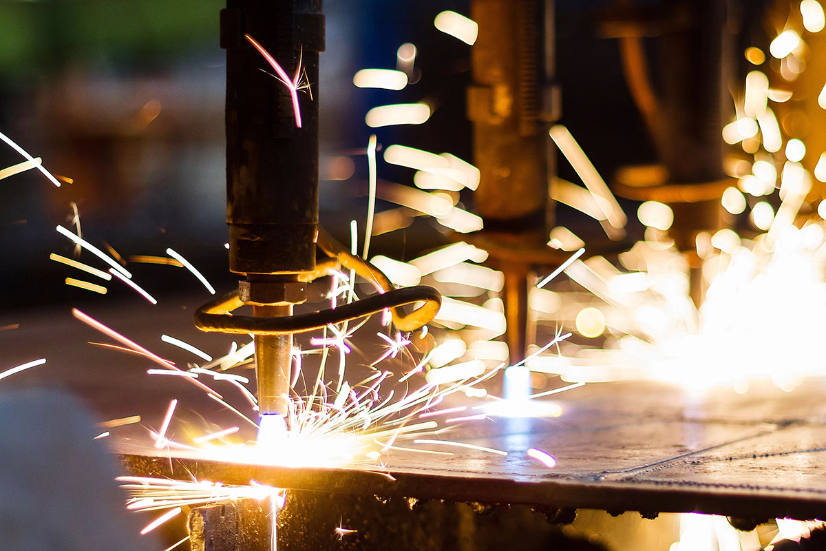 Close-up of welding equipment producing bright sparks as it cuts through metal, with a blurred background focused on the intensity of the sparks and welding process.
