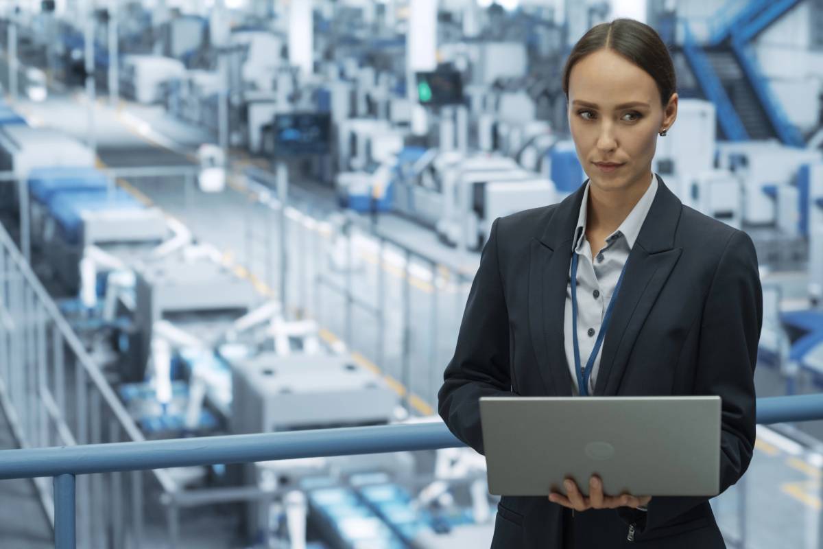A woman in a factory reviewing the company's CMMC Level 1 compliance.